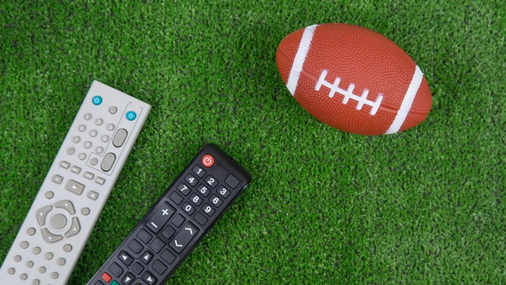 A football and remote controls on green turf