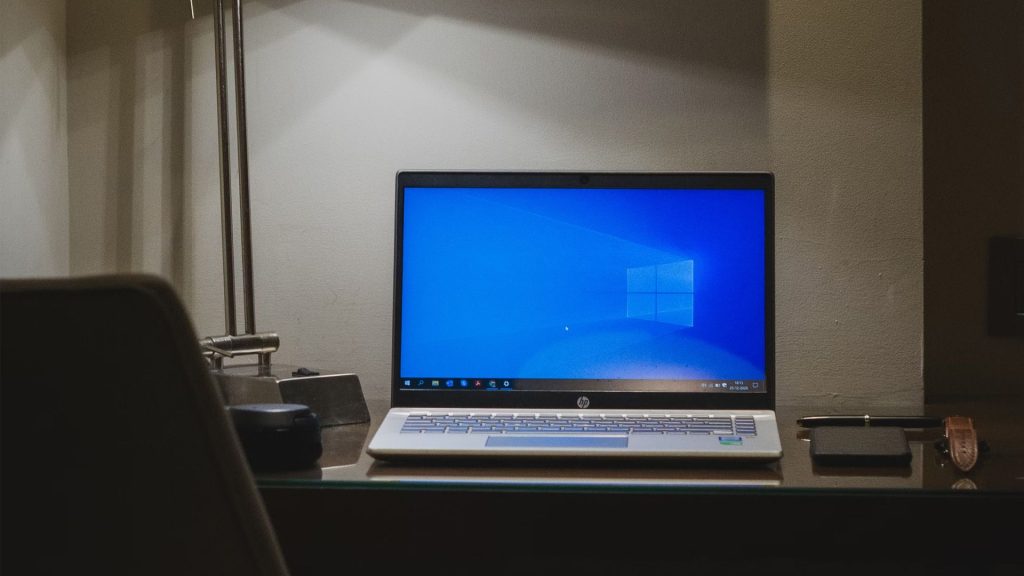 Windows 10 laptop sitting on a desk in a dark room.