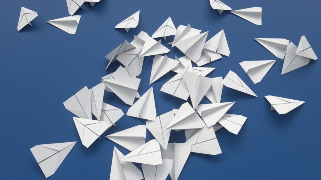 Ryanair tries forcing app downloads by eliminating paper boarding passes High angle view of white paper airplanes on blue background